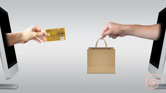 An image with a computer screen in the middle and two hands exchanging a credit card and a shopping bag in front of it.