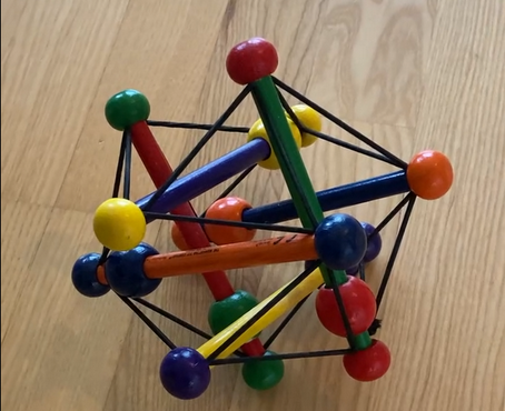 A picture of a colorful toy made of sticks that are not touching each other, but are connected by a bunch of rubber bands.